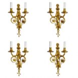 Four intricate gilded sconces with currency curls crowned with cherubs.