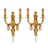 A pair of gilded sconces, with currency curls, surmounted by cherubs.