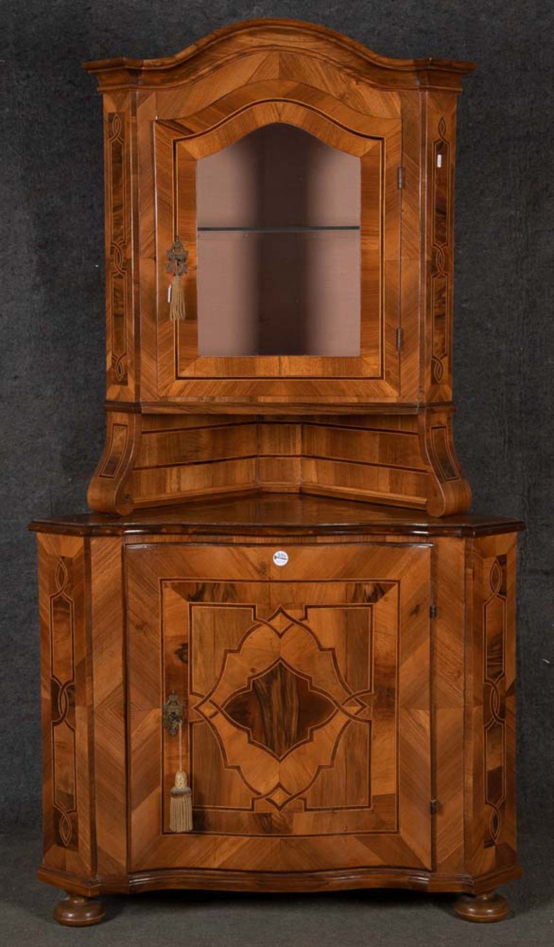 Eckschrank. Deutsch 18./19. Jh. Nussbaumfurnier, Bandelwerk, teilw. massiv, Kugelfüße, gebauchte