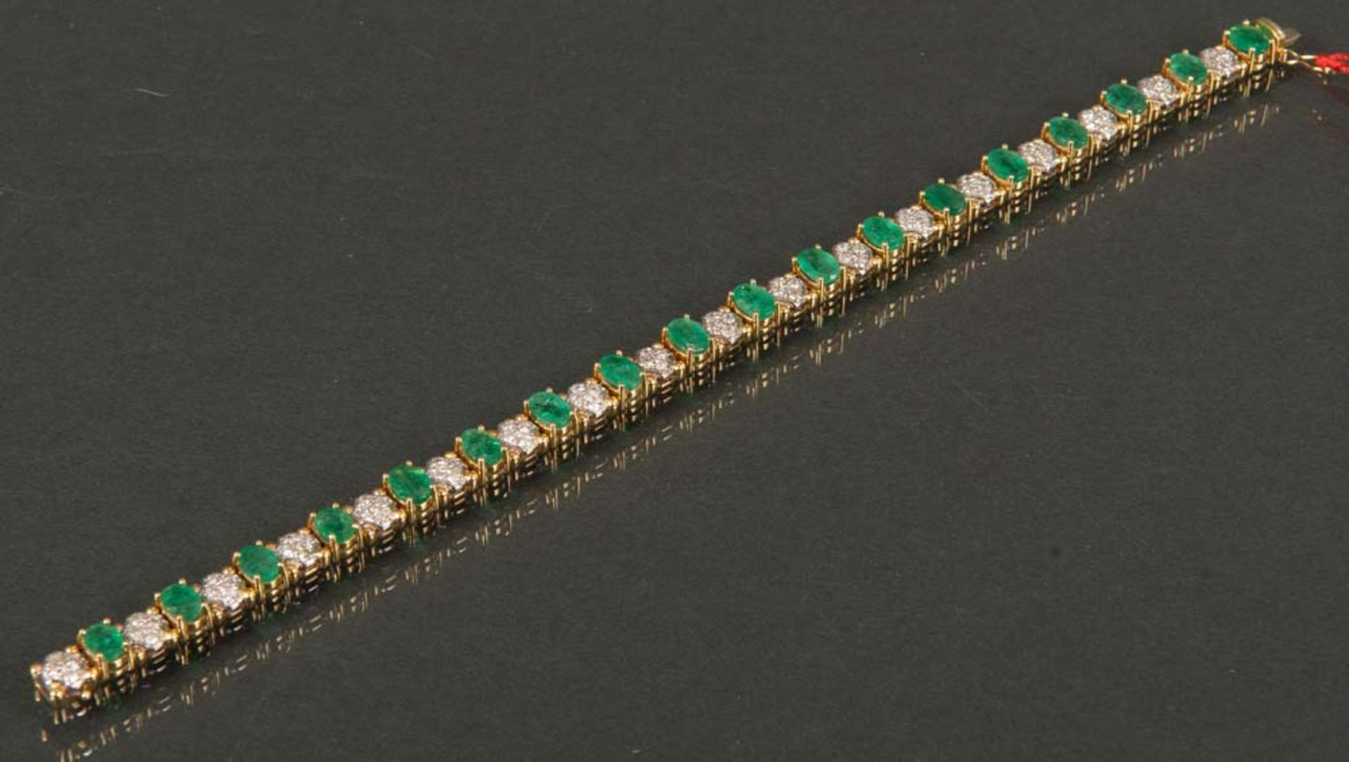 Damenarmband. 18 ct Gold, ca. 18,3 g, besetzt mit Brillanten, ca. 1,00 ct, und smaragdfarbigen