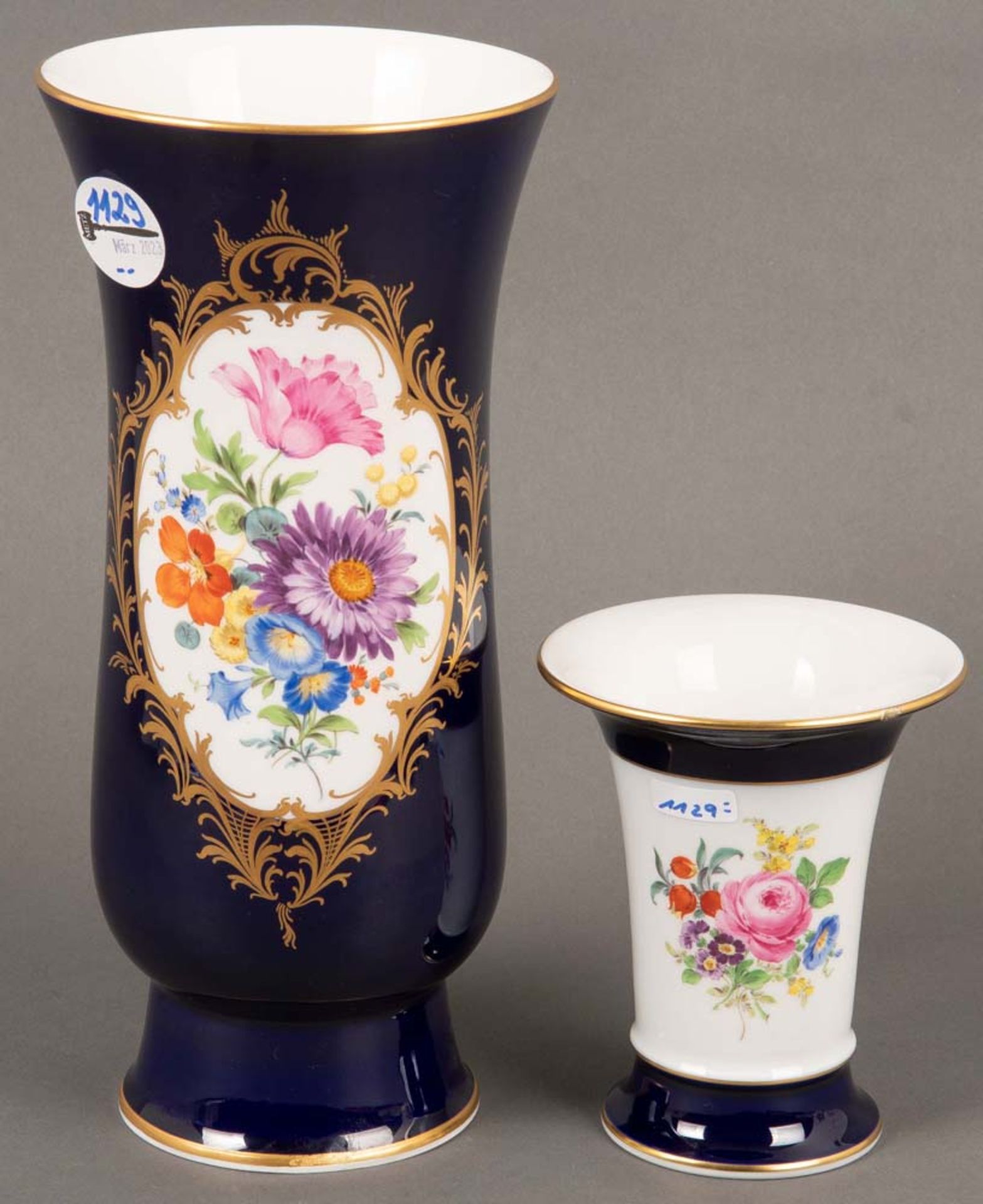 Zwei Vasen. Meissen 20. Jh. Porzellan, kobaltblauer Fond mit Goldrand, Schauseiten bunt bemalt mit