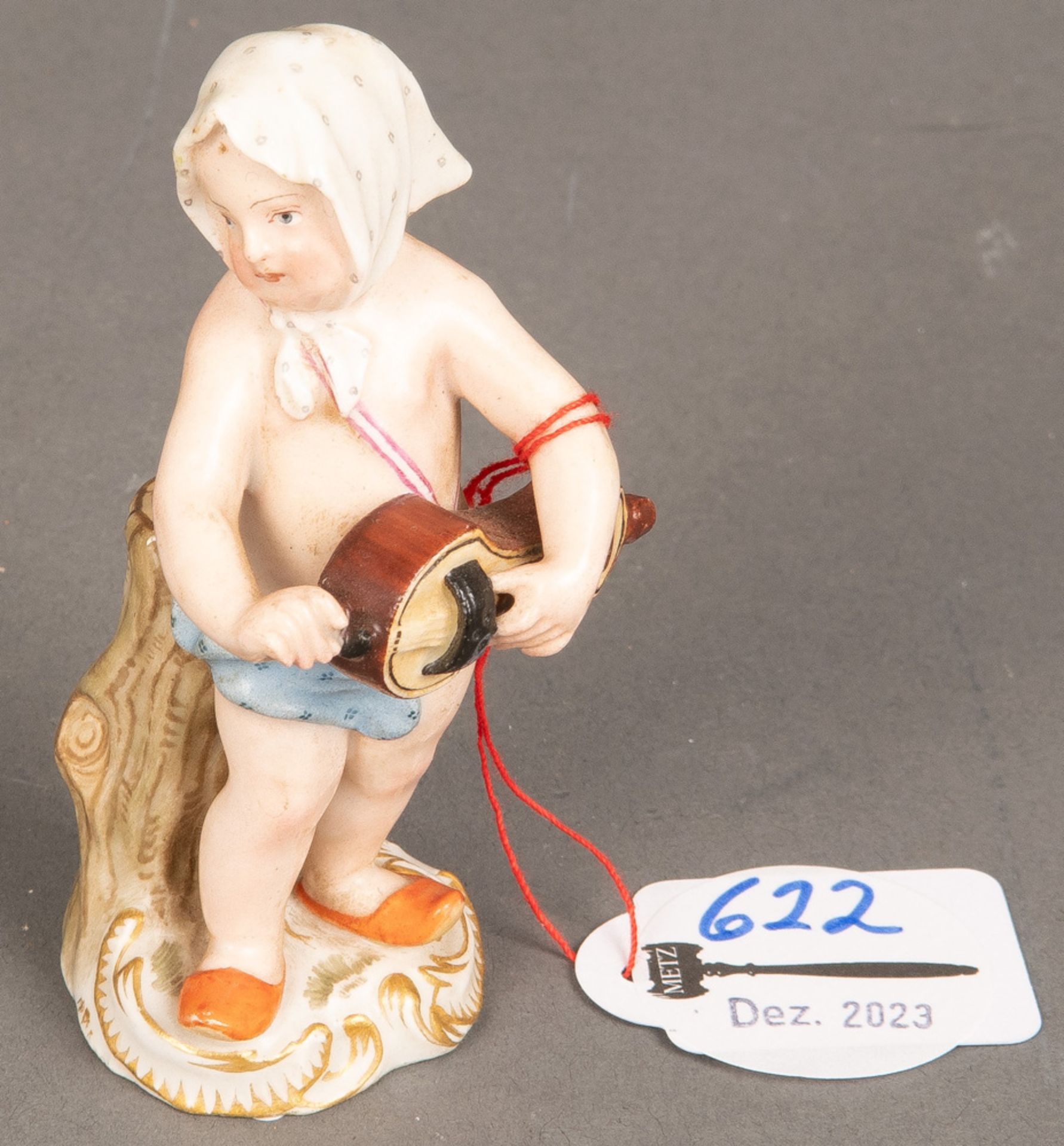 Putto als Drehleierspielerin. Meissen 19. Jh. Porzellan, bunt bemalt. Am Boden schwach erkennbare