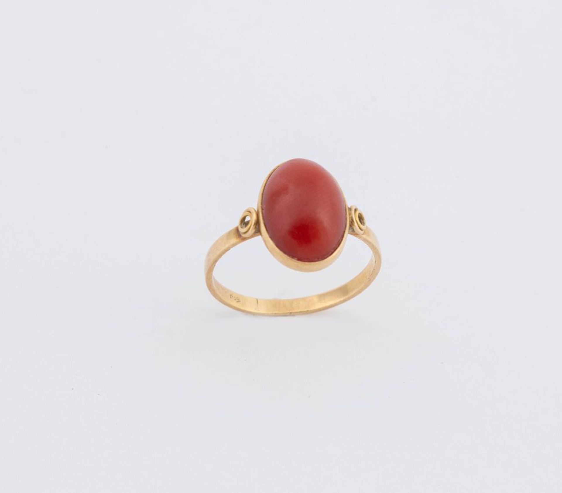 Anello in oro giallo 18K, centrato da cabochon ovale di corallo rosso mediterraneo. Peso complessivo