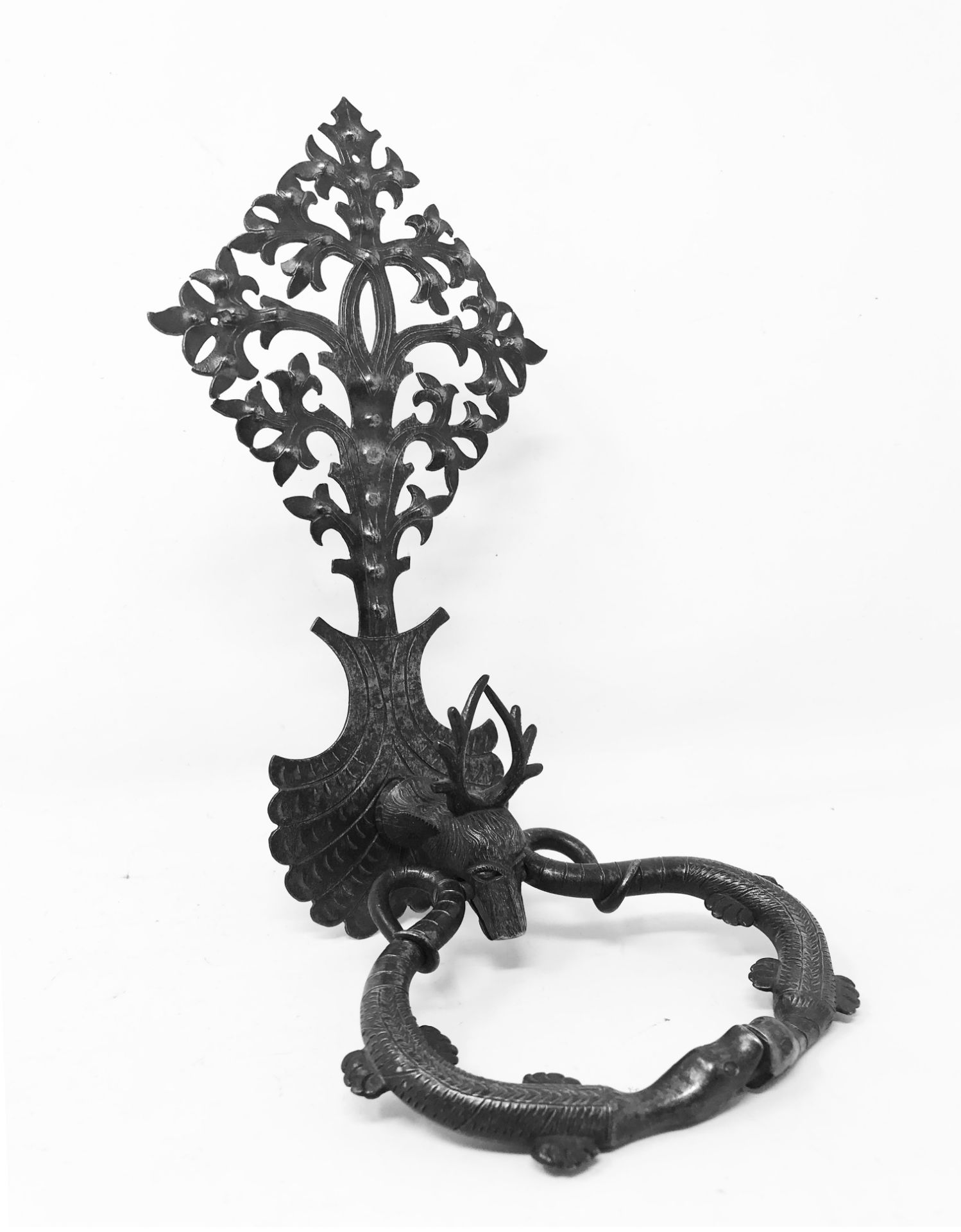 Wrought and chiseled iron door knocker carved with a stag's head, holding the ring formed by two