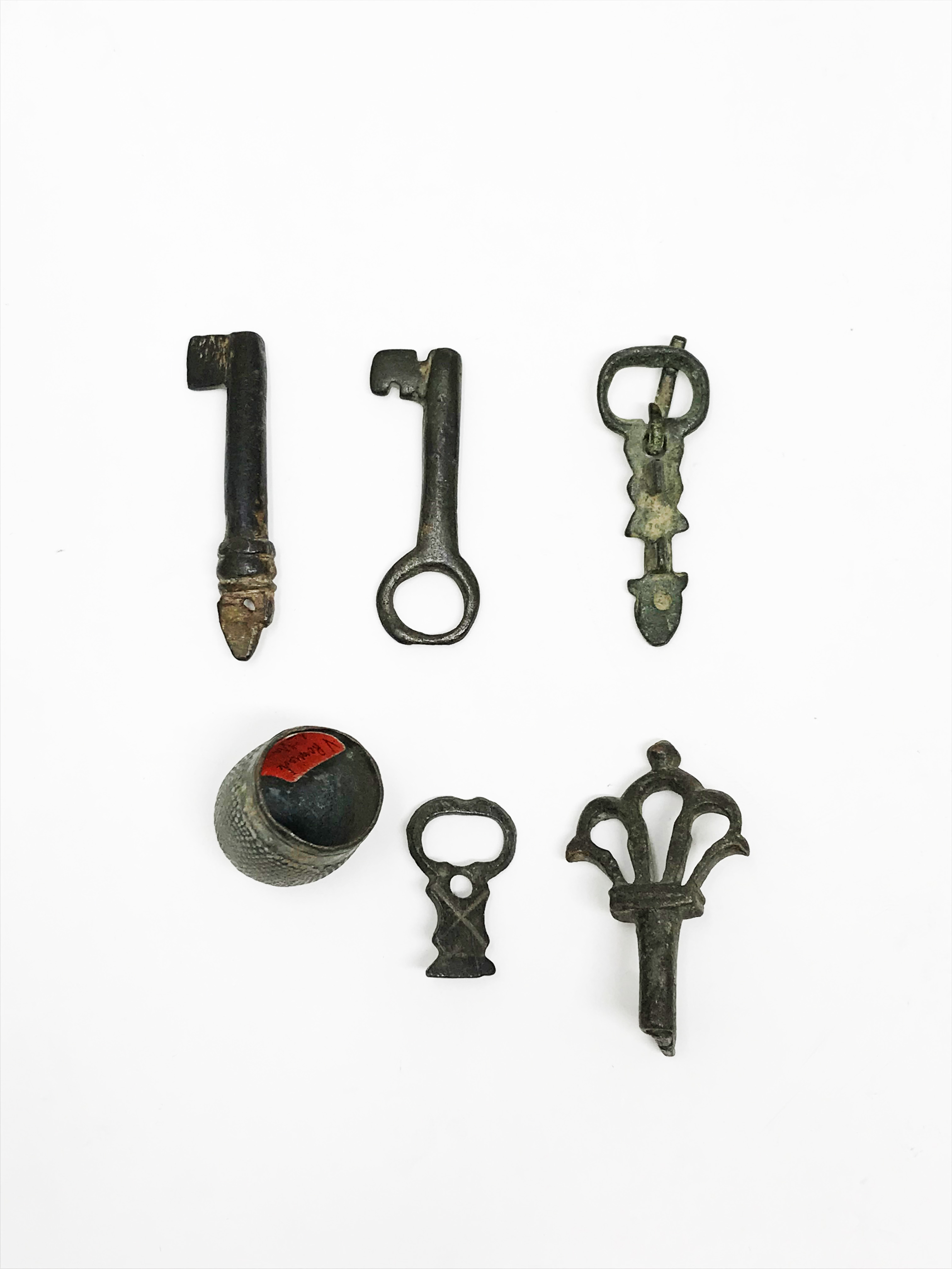 Two bronze belt buckles, three bronze keys, a thimble.H: 3,05 cm - 5,52 cm - 5,15 cm - 5,33 cm - 5,