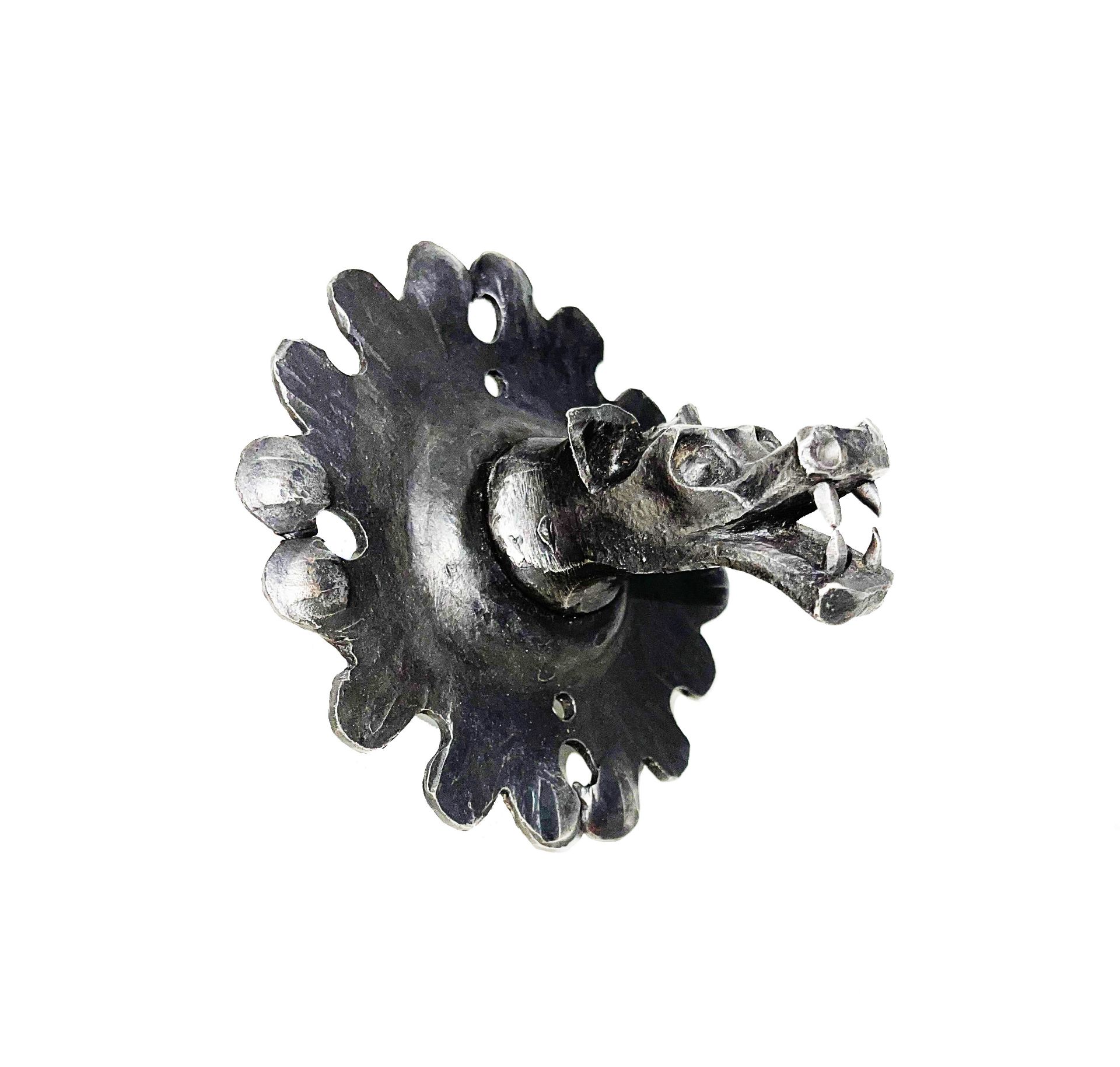 Wrought iron pull handle in the shape of a roaring monster's mouth on a poly-lobed plate in repoussé