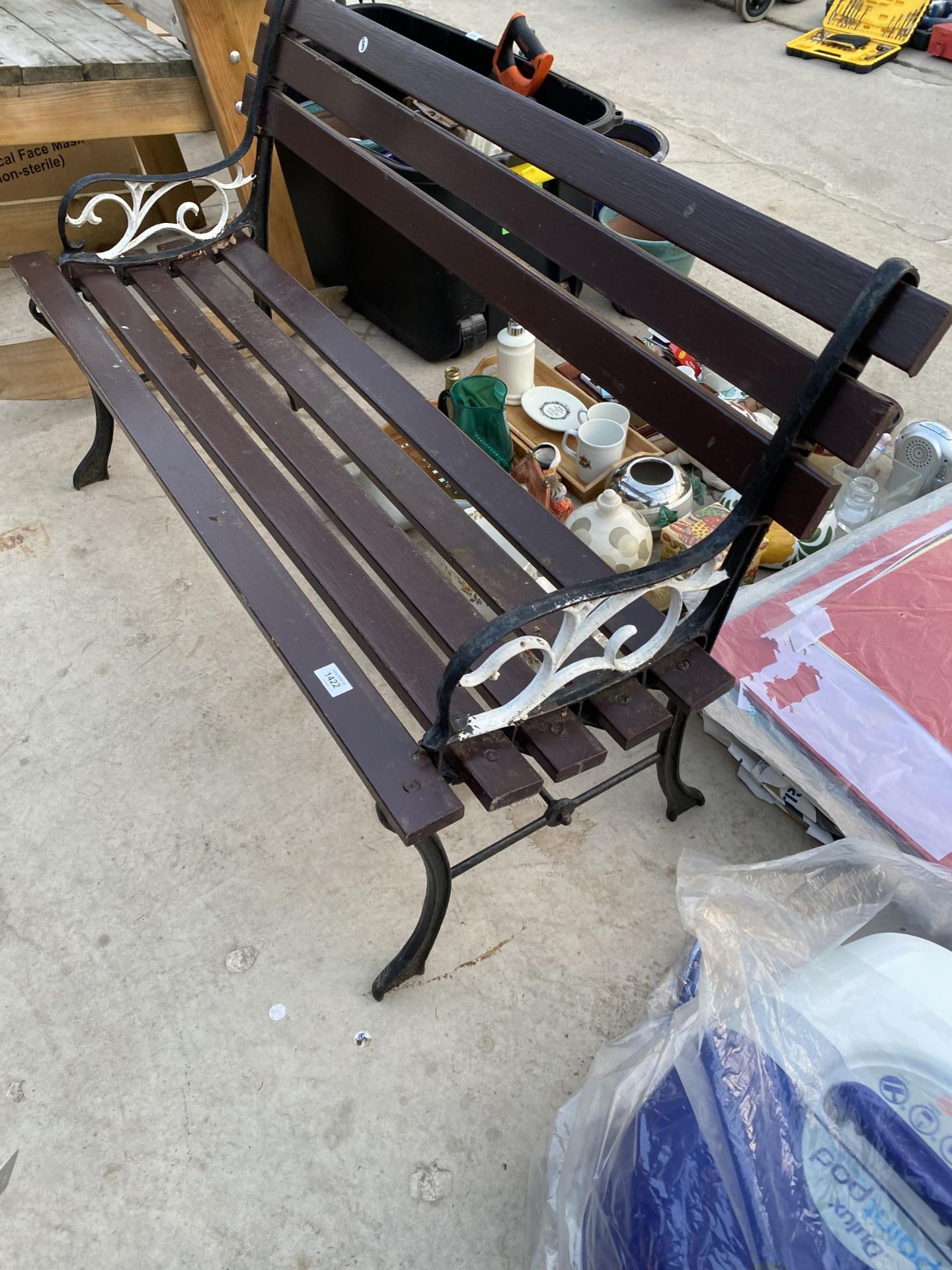 A WOODEN SLATTED GARDEN BENCH WITH CAST BENCH ENDS