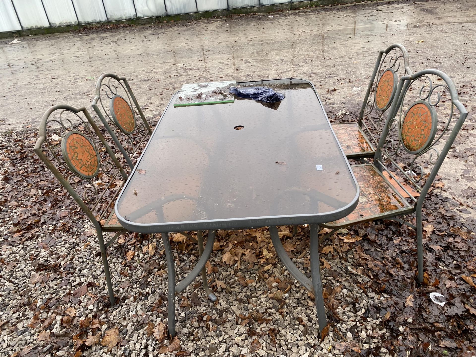 A GLASS TOPPED METAL GARDEN TABLE AND FOUR CHAIRS