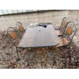 A GLASS TOPPED METAL GARDEN TABLE AND FOUR CHAIRS