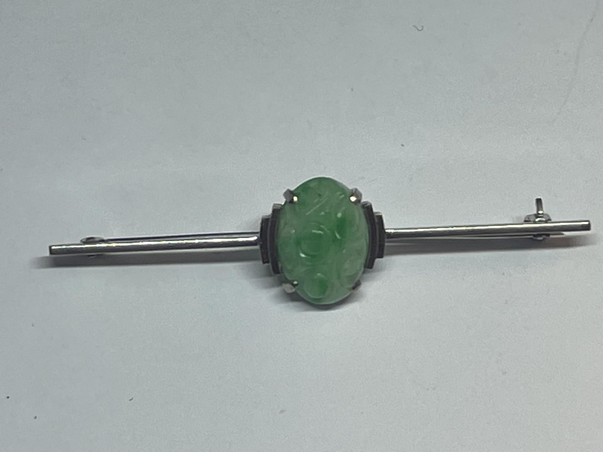 A 9 CARAT WHITE GOLD BROOCH WITH A CENTRE JADE STONE GROSS WEIGHT 3.7 GRAMS IN A PRESENTATION BOX