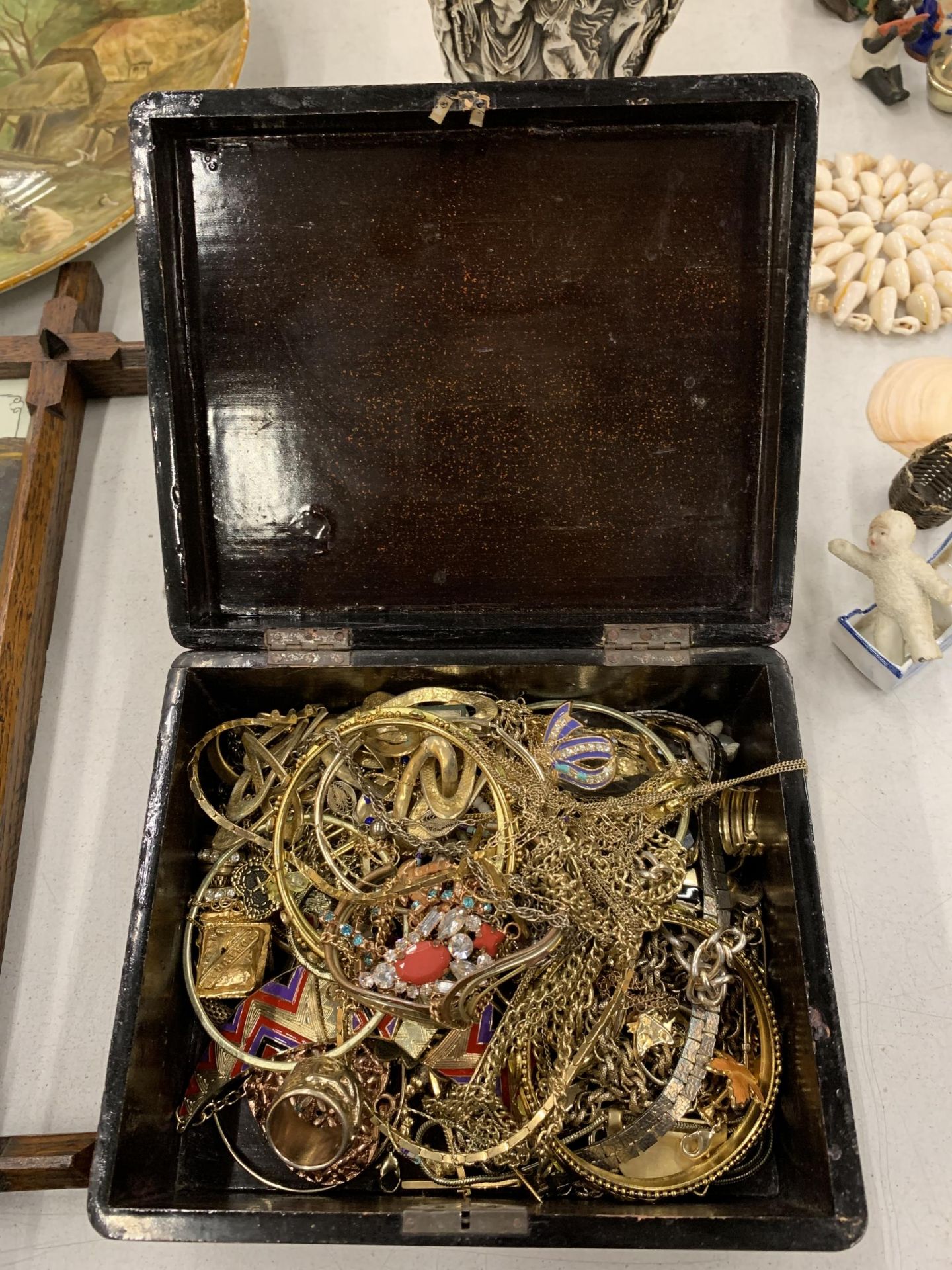 AN ORIENTAL STYLE LACQUERED BOX CONTAINING A QUANTITY OF YELLOW METAL COSTUME JEWELLERY TO INCLUDE