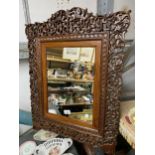 A 20TH CENTURY HARDWOOD WALL MIRROR WITH CARVED FOLIATE AND ANIMAL AND BIRD DECORATION 69CM X 56CM