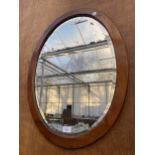 AN OVAL MAHOGANY FRAMED BEVELED EDGE WALL MIRROR