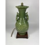 A YUAN DYNASTY STYLE CHINESE GREEN STONEWARE LAMP BASE WITH LOOP HANDLES ON CARVED WOODEN BASE,