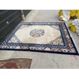 A LARGE CREAM AND BLUE PATTERNED FRINGED RUG