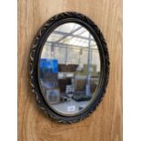 A SMALL OVAL GILT AND BLACK FRAMED WALL MIRROR