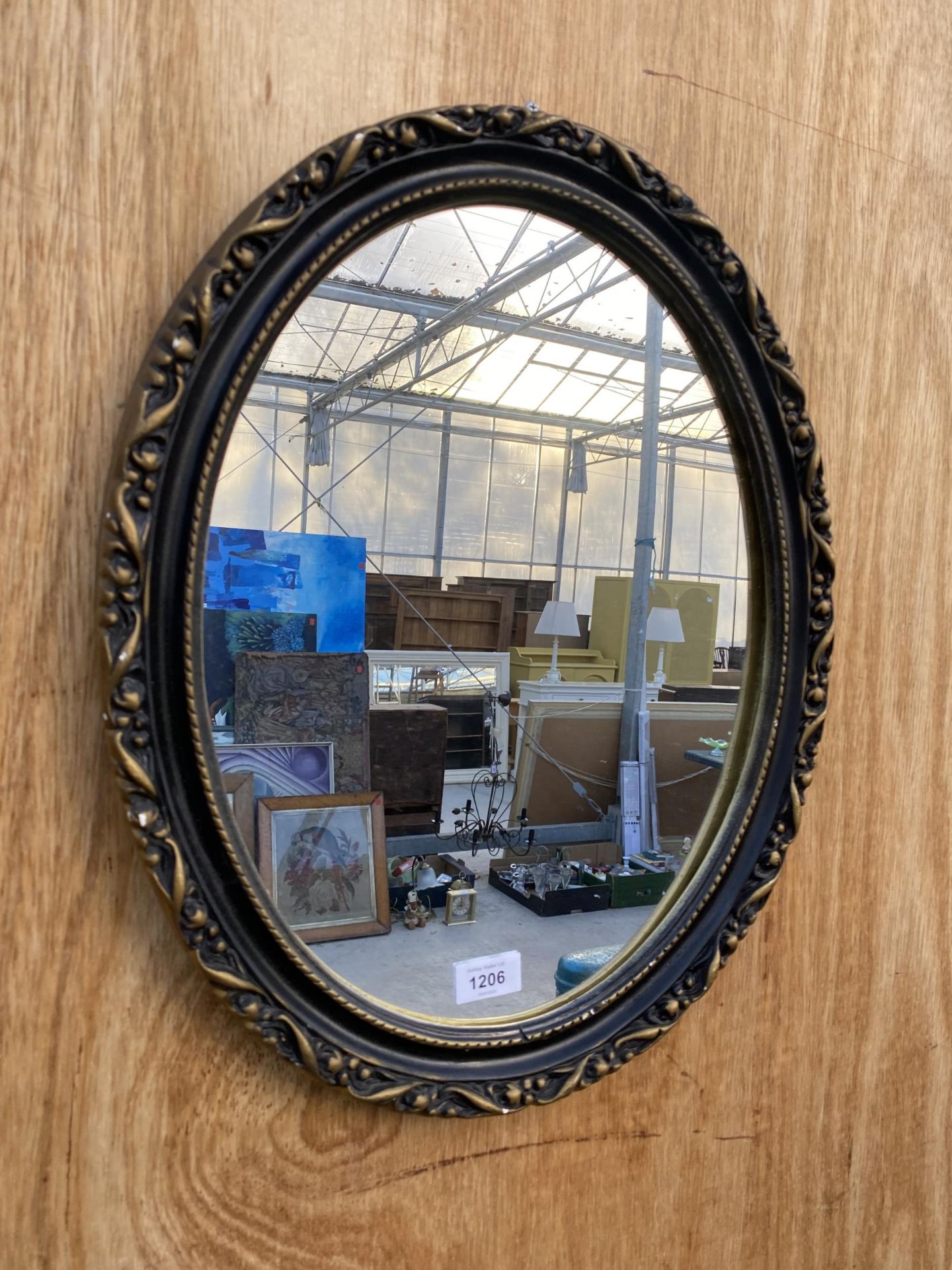 A SMALL OVAL GILT AND BLACK FRAMED WALL MIRROR