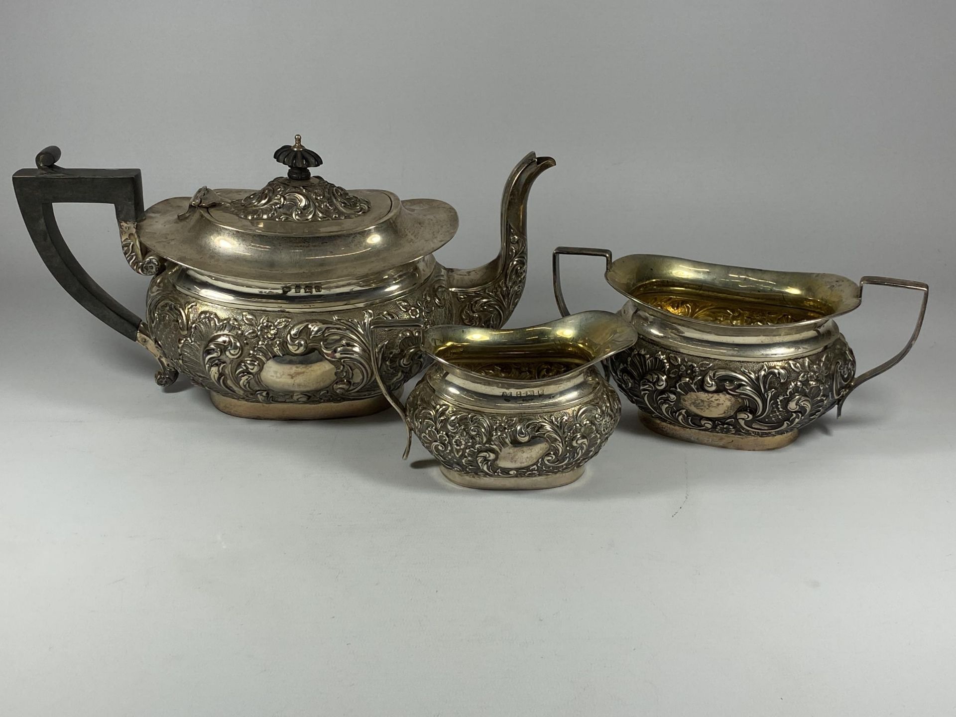 AN EDWARDIAN SILVER THREE PIECE TEA SET COMPRISING TEAPOT, SUGAR BOWL AND CREAM JUG, HALLMARKS FOR