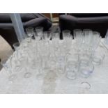 A LARGE ASSORTMENT OF GLASS WARE TO INCLUDE WINE GLASSES AND CHAMPAGNE FLUTES ETC