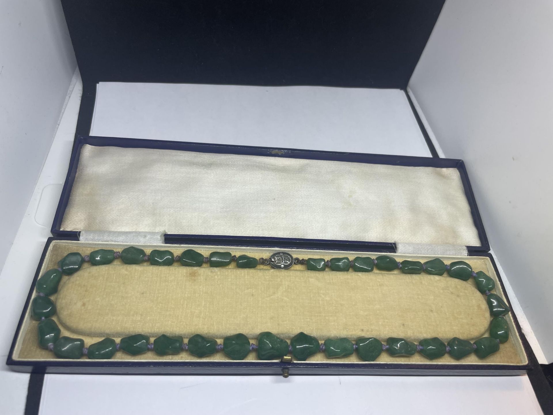 A JADE KNOTTED NECKLACE WITH A MARKED SILVER CLASP IN A PRESENTATION BOX