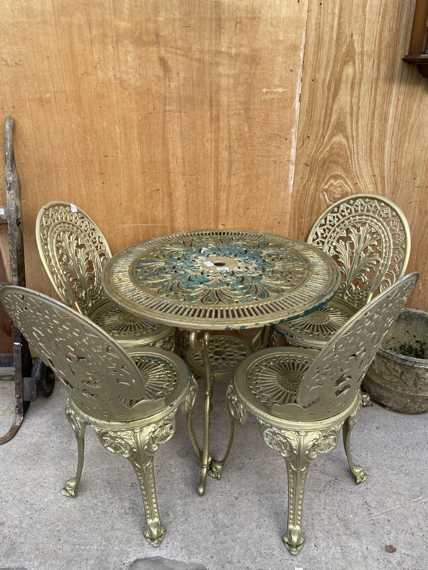 A VINTAGE STYLE CAST ALLOY BISTRO SET COMPRISING OF A ROUND TABLE AND FOUR CHAIRS