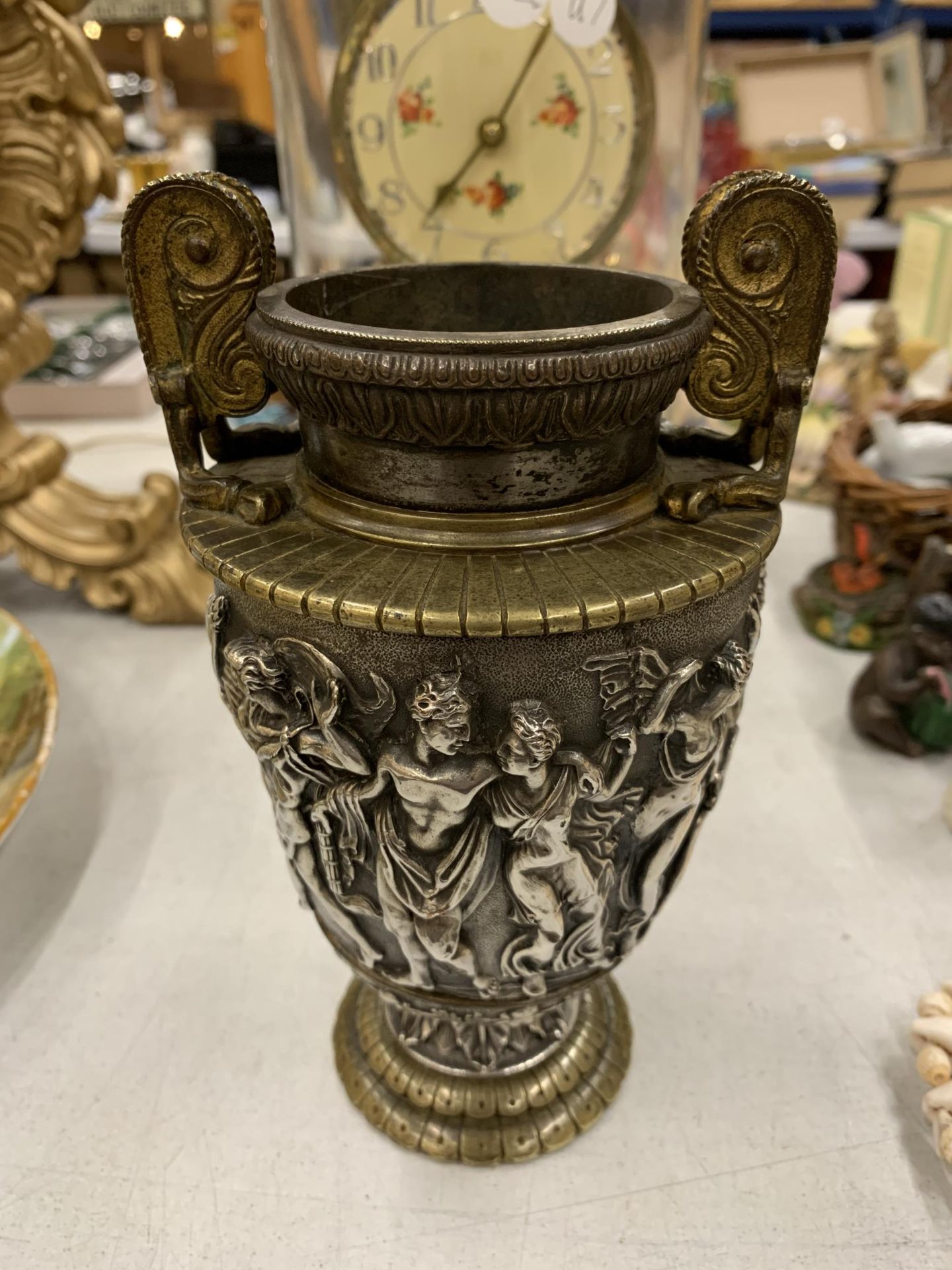 A YELLOW AND WHITE METAL GRECIAN STYLE URN WITH EMBOSSED GREEK FIGURES HEIGHT 17CM