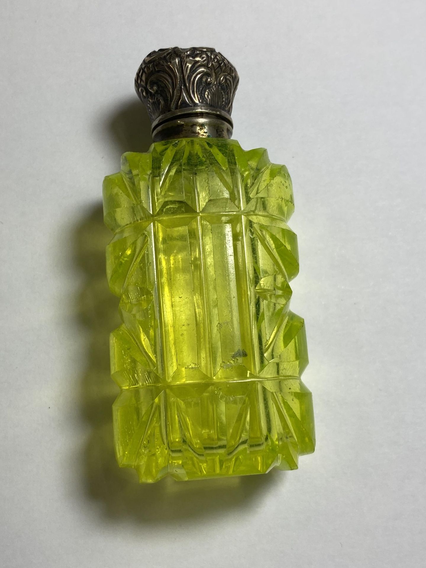 A CUT GLASS AND AND WHITE METAL TOPPED PERFUME BOTTLE, BELIEVED SILVER