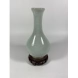 A CHINESE CELADON GROUND PORCELAIN BOTTLE VASE ON CARVED WOODEN STAND, HEIGHT OF VASE 18CM