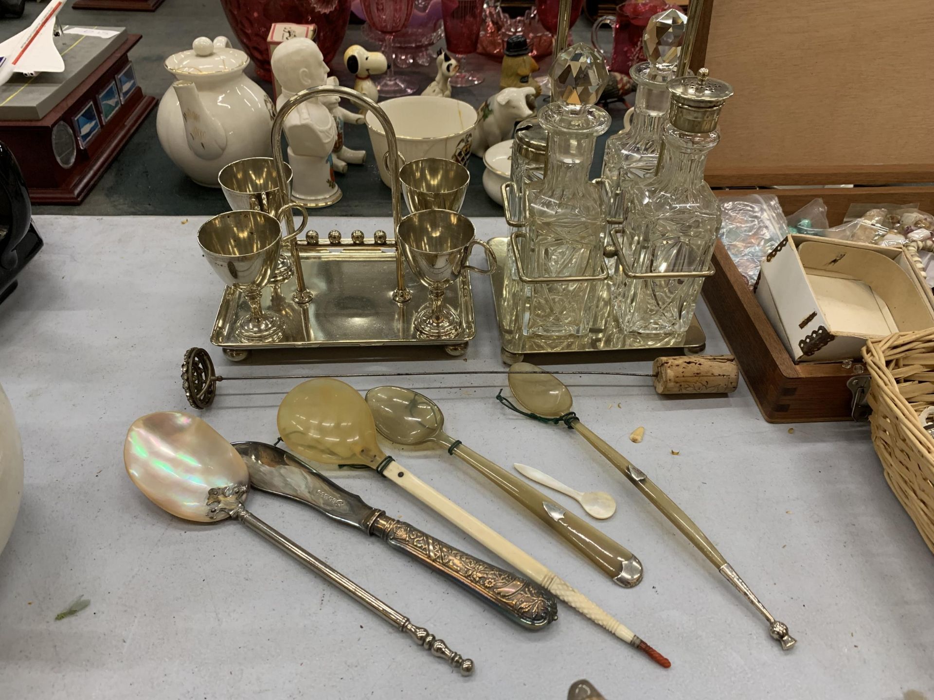 A CUT GLASS CRUET SET WITH PLATED TOPS IN A HOLDER, SILVER PLATED EGG CUPS ON A TRAY, SERVING