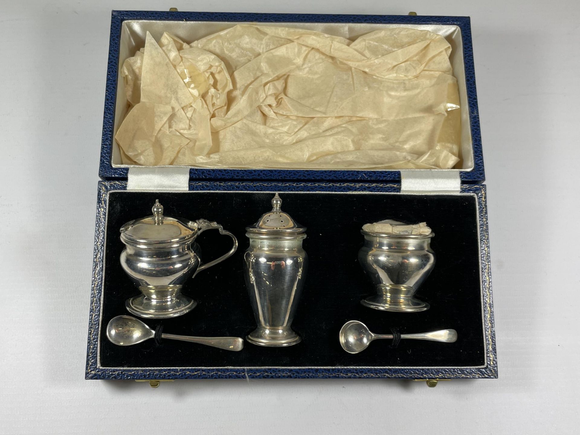 A CASED SILVER CONDIMENT SET COMPRISING MUSTARD POT & SPOON, PEPPERETTE & OPEN SALT & SPOON,