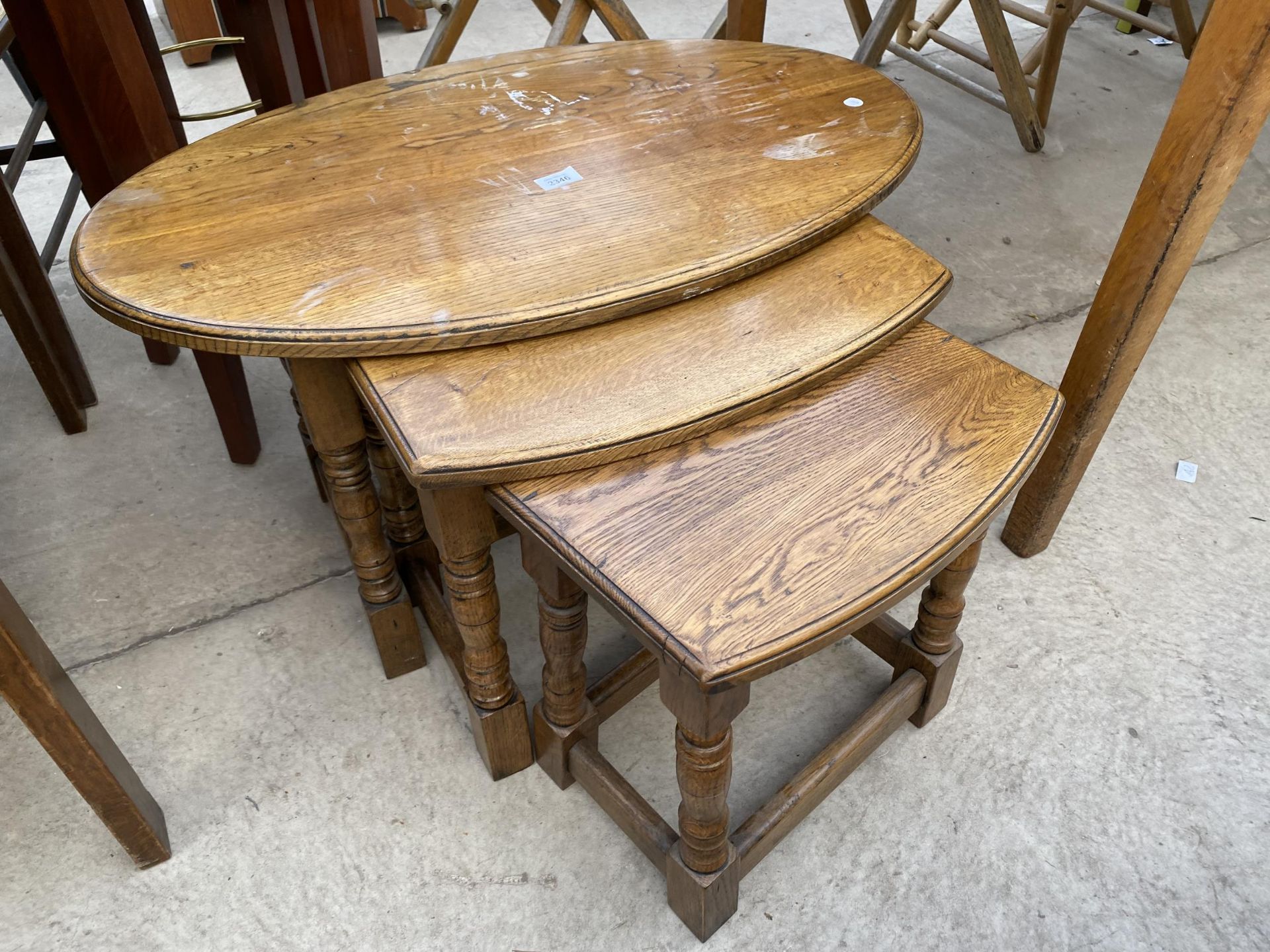 AN OVAL OAK NEST OF THREE TABLES ON TURNED LEGS