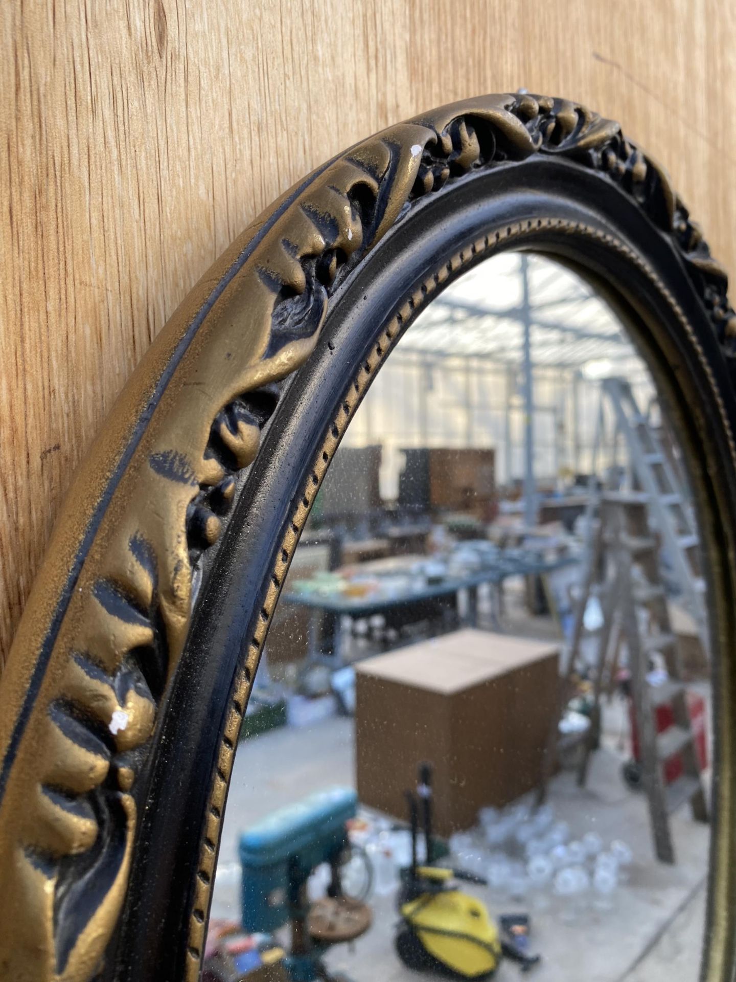 A SMALL OVAL GILT AND BLACK FRAMED WALL MIRROR - Image 3 of 3