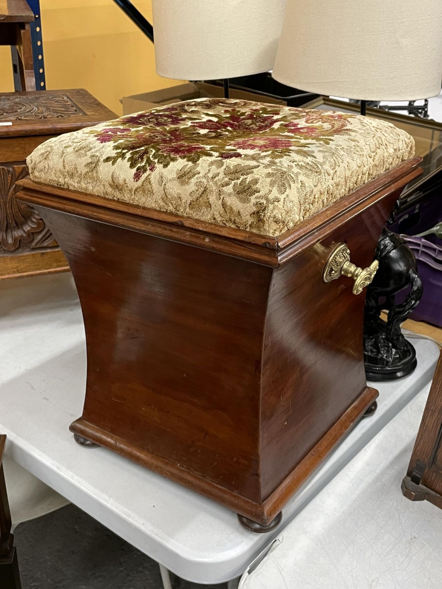 A MAHOGANY OTTOMAN ON BUN FEET WITH BRASS HANDLES AND FLORAL EMBROIDERED SEAT