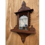 A DECORATIVE WOODEN FRAMED WALL MIRROR WITH LOWER SHELF