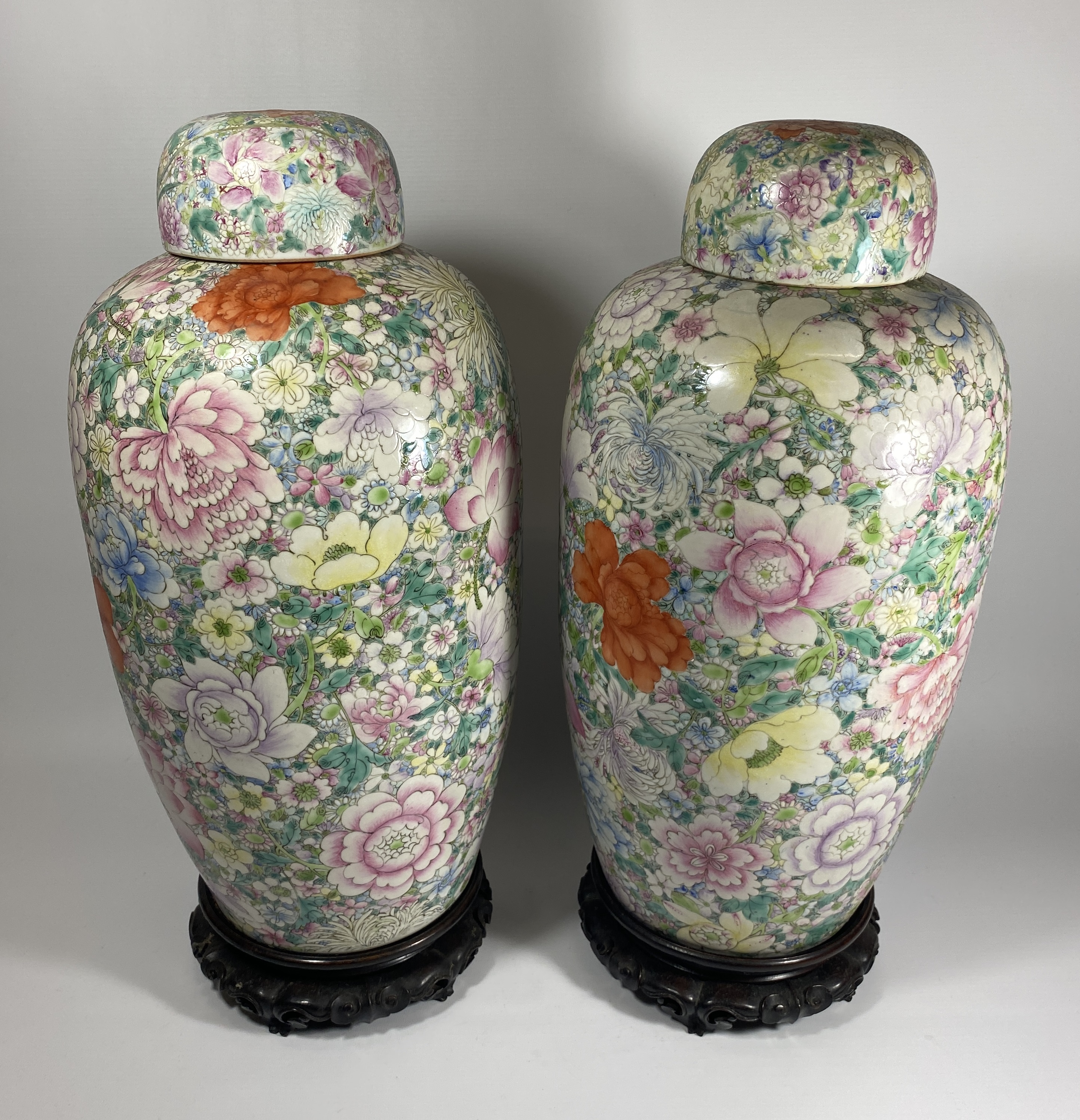 A PAIR OF LATE 19TH CENTURY CHINESE QING FLORAL DESIGN LIDDED JARS ON WOODEN STANDS, QIANLONG MARK