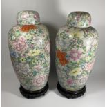 A PAIR OF LATE 19TH CENTURY CHINESE QING FLORAL DESIGN LIDDED JARS ON WOODEN STANDS, QIANLONG MARK