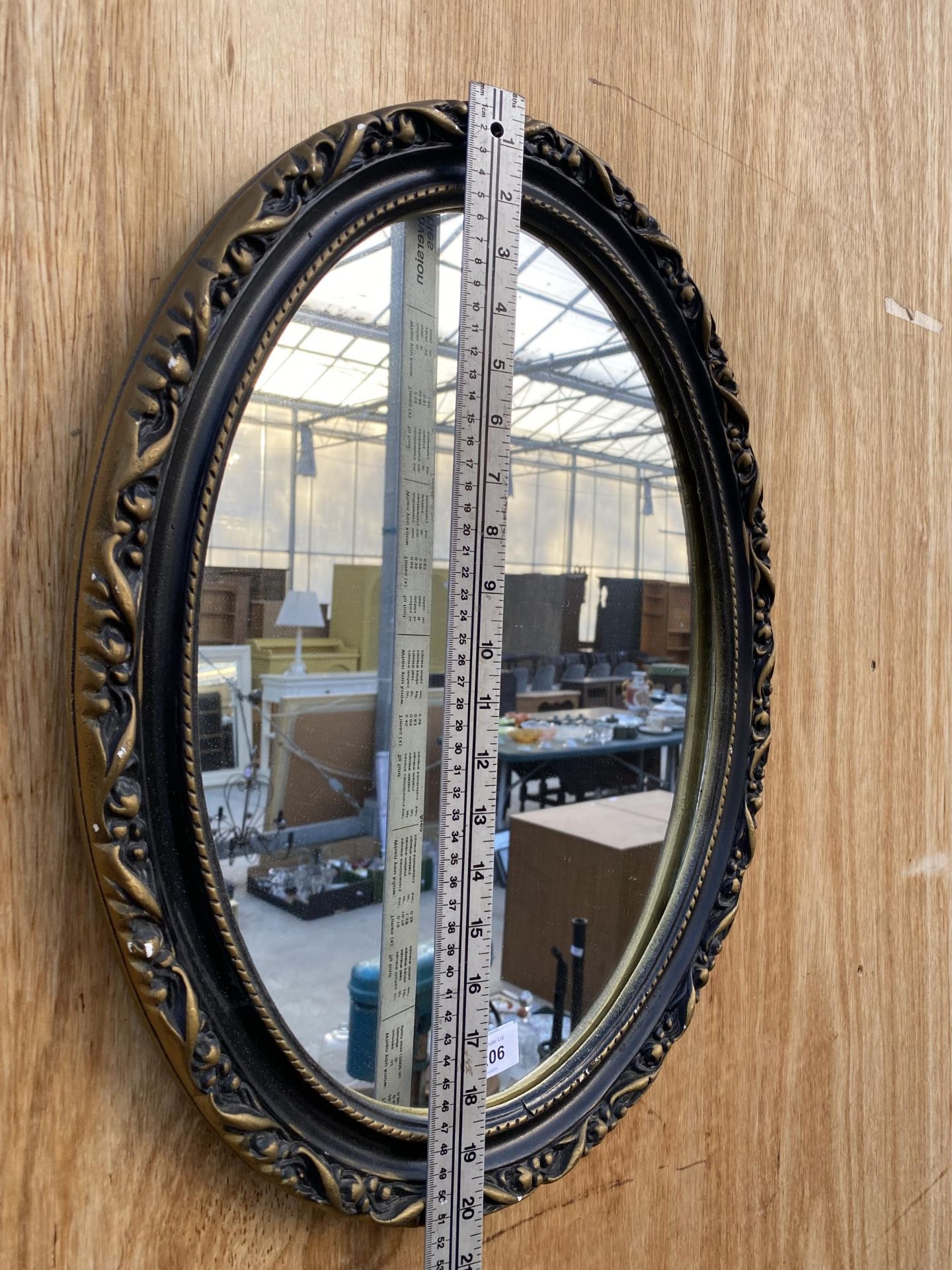 A SMALL OVAL GILT AND BLACK FRAMED WALL MIRROR - Image 2 of 3