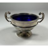 A GEORGE V SILVER TWIN HANDLED PEDESTAL BOWL WITH BLUE GLASS LINER, HALLMARKS FOR BIRMINGHAM, 1913
