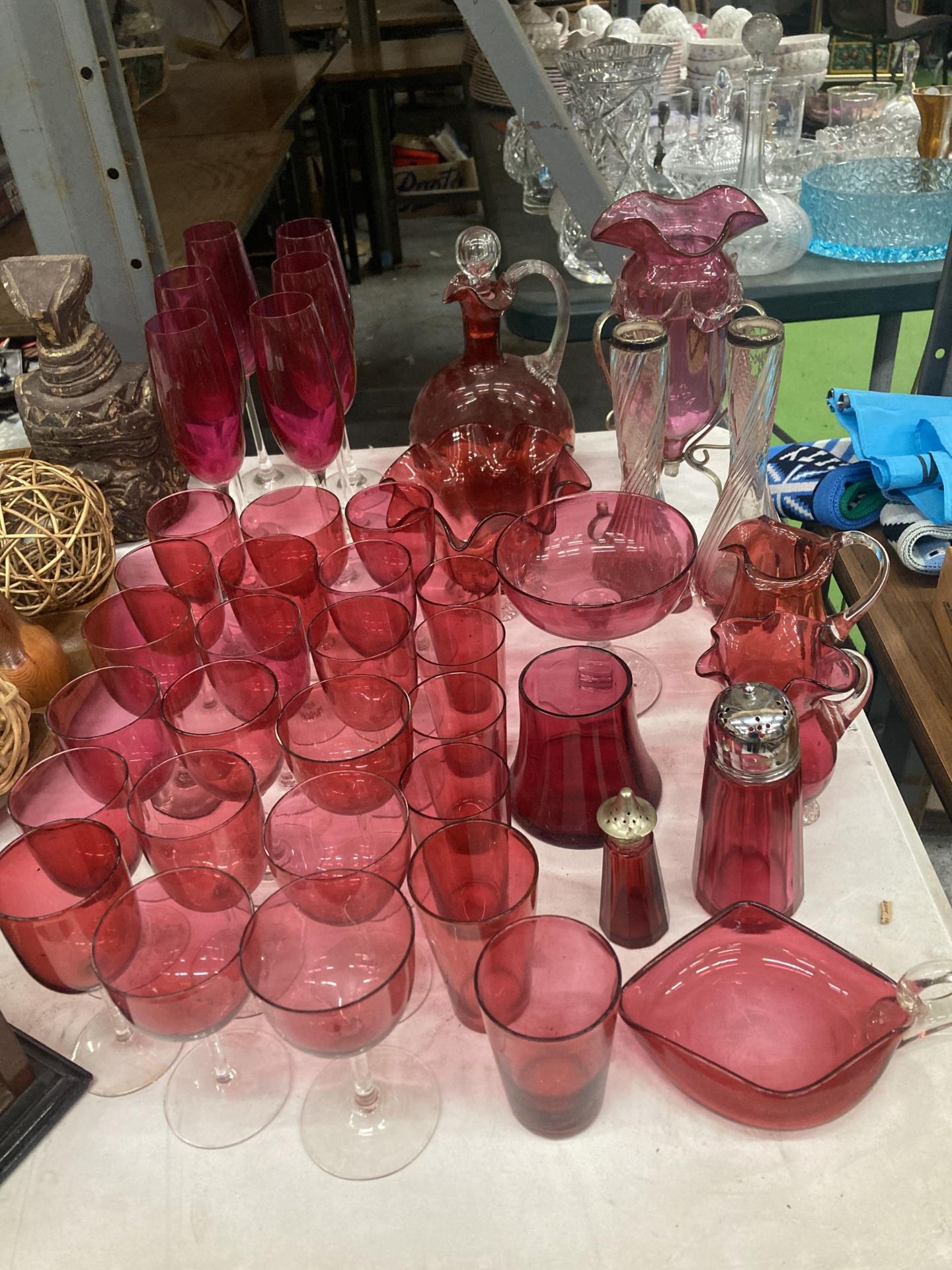 A LARGE QUANTITY OF CRANBERRY GLASS TO INCLUDE DRINKING GLASSES, VASES, JUGS, DECANTER, ETC.,