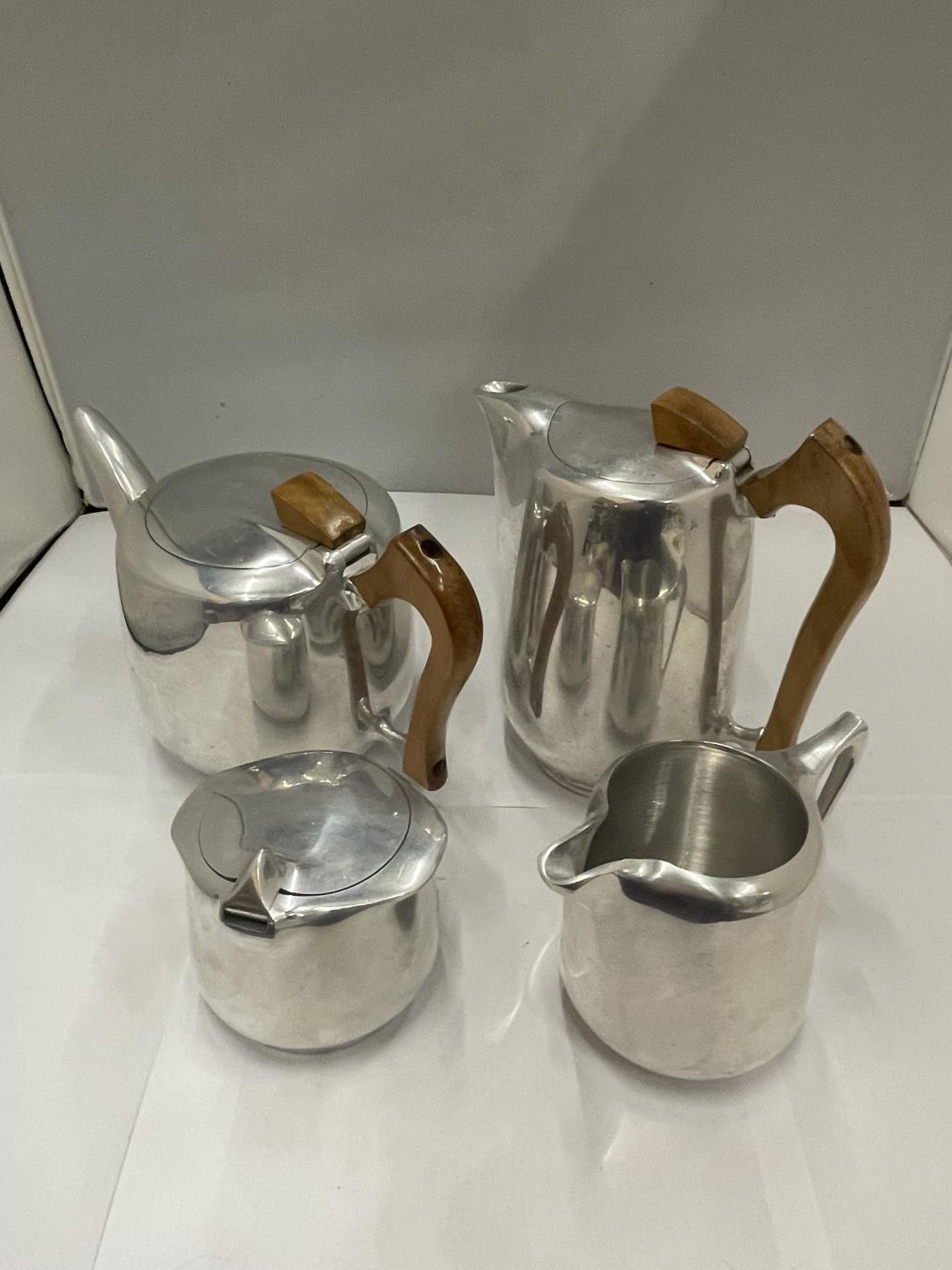 A PICQUOT WARE STAINLESS STEEL TEAPOT, COFFEE POT, SUGAR BOWL AND CREAM JUG