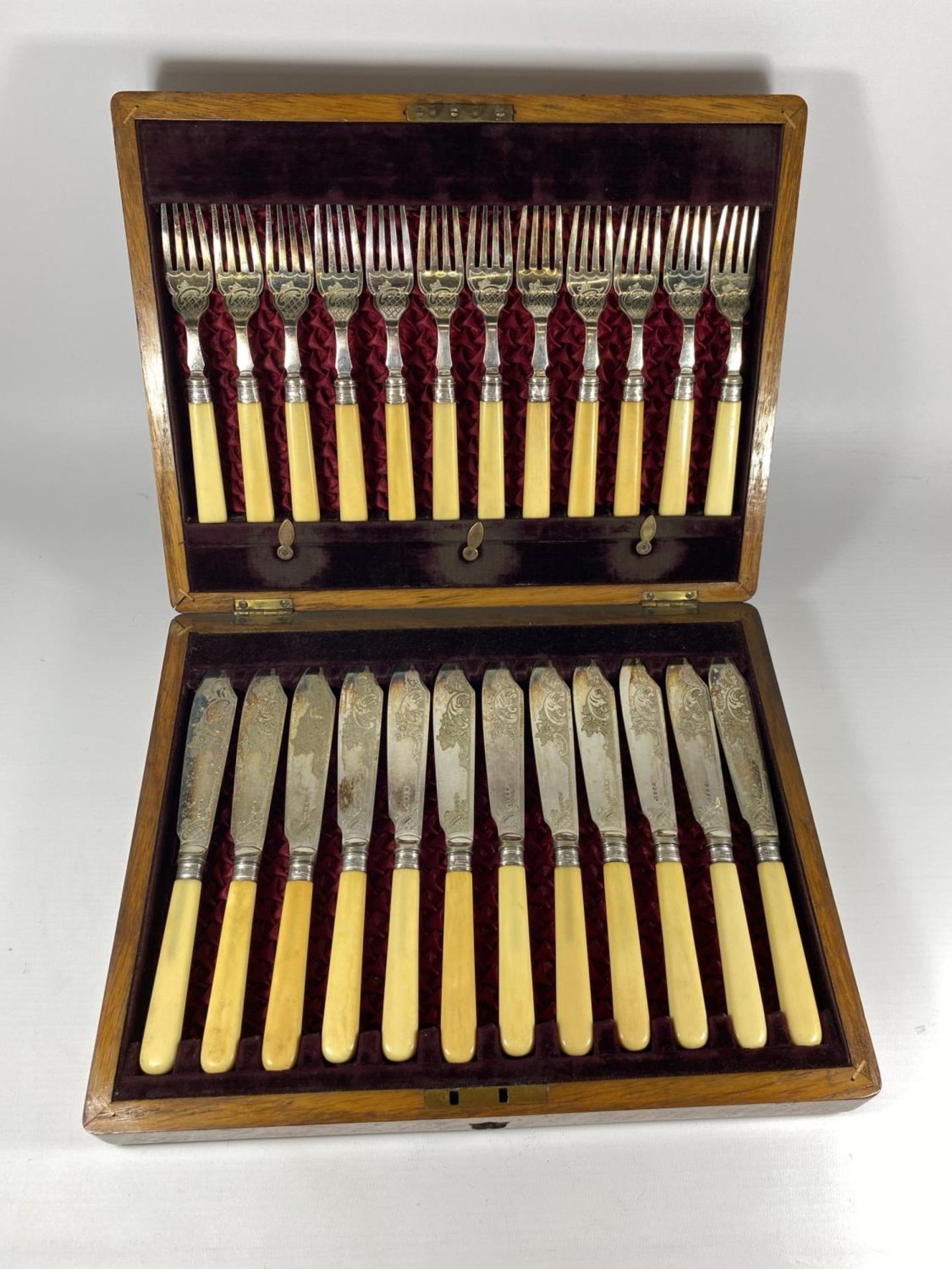 AN OAK CASED CANTEEN OF CUTLERY WITH SHEFFIELD SILVER FERRULES & RED LINED INTERIOR