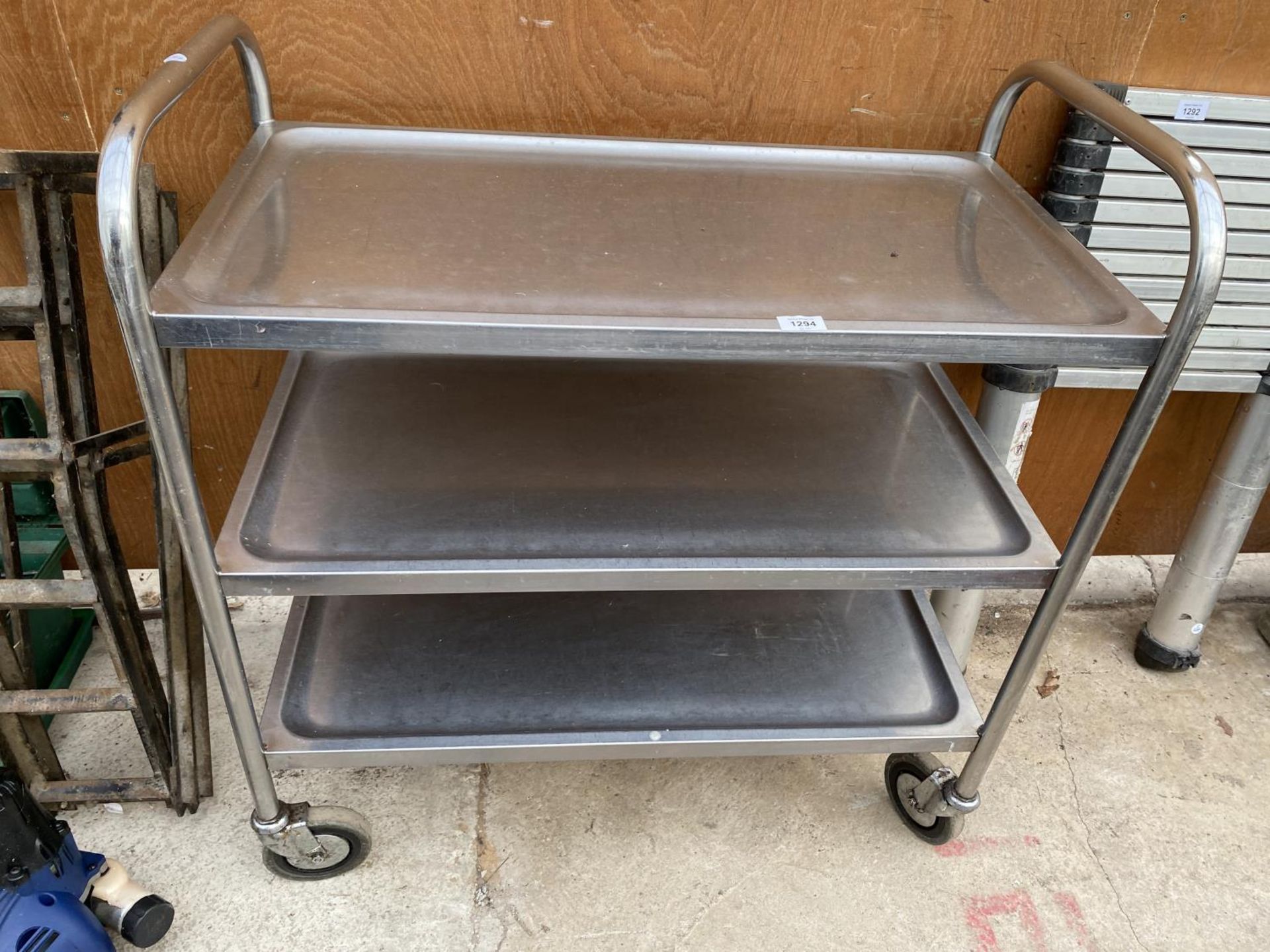 A STAINLESS STEEL FOUR WHEELED THREE TIER TROLLEY