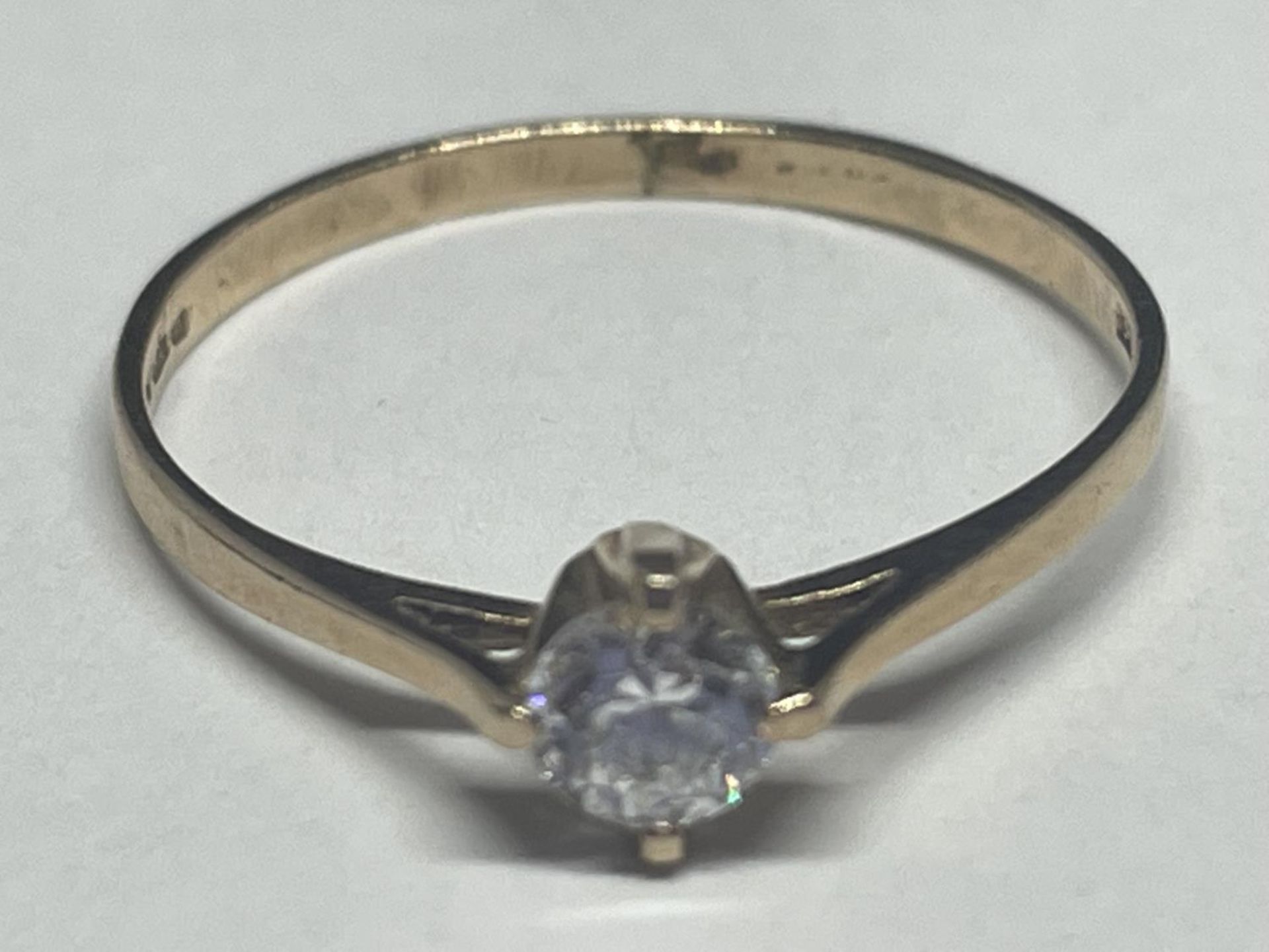 A 9 CARAT GOLD RING WITH A SOLITAIRE CLEAR STONE SIZE O/P
