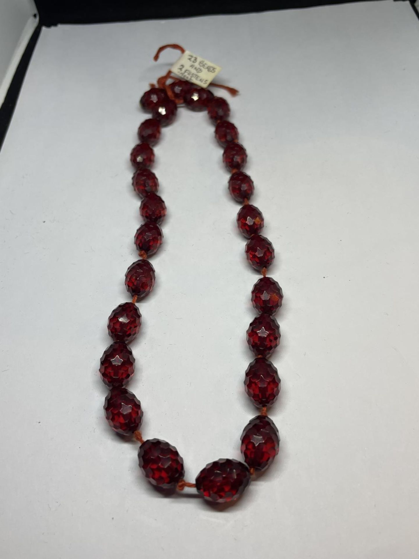 AN AMBER EFFECT BEADED NECKLACE WITH TWENTY THREE BEADS AND TWO FASTNER BEADS