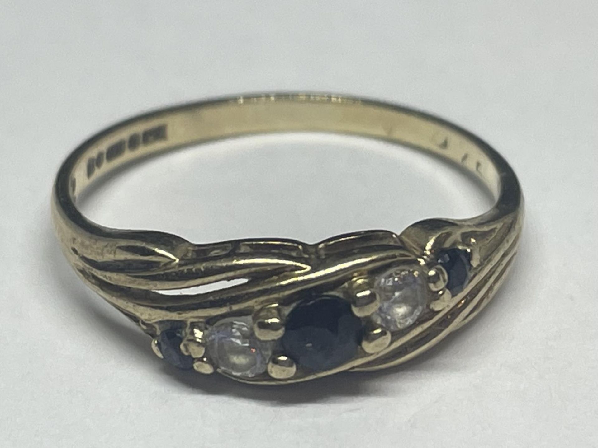 A 9 CARAT GOLD RING WITH THREE SAPPHIRES AND TWO CUBIC ZIRCONIAS ON A TWIST DESIGN SIZE M/N