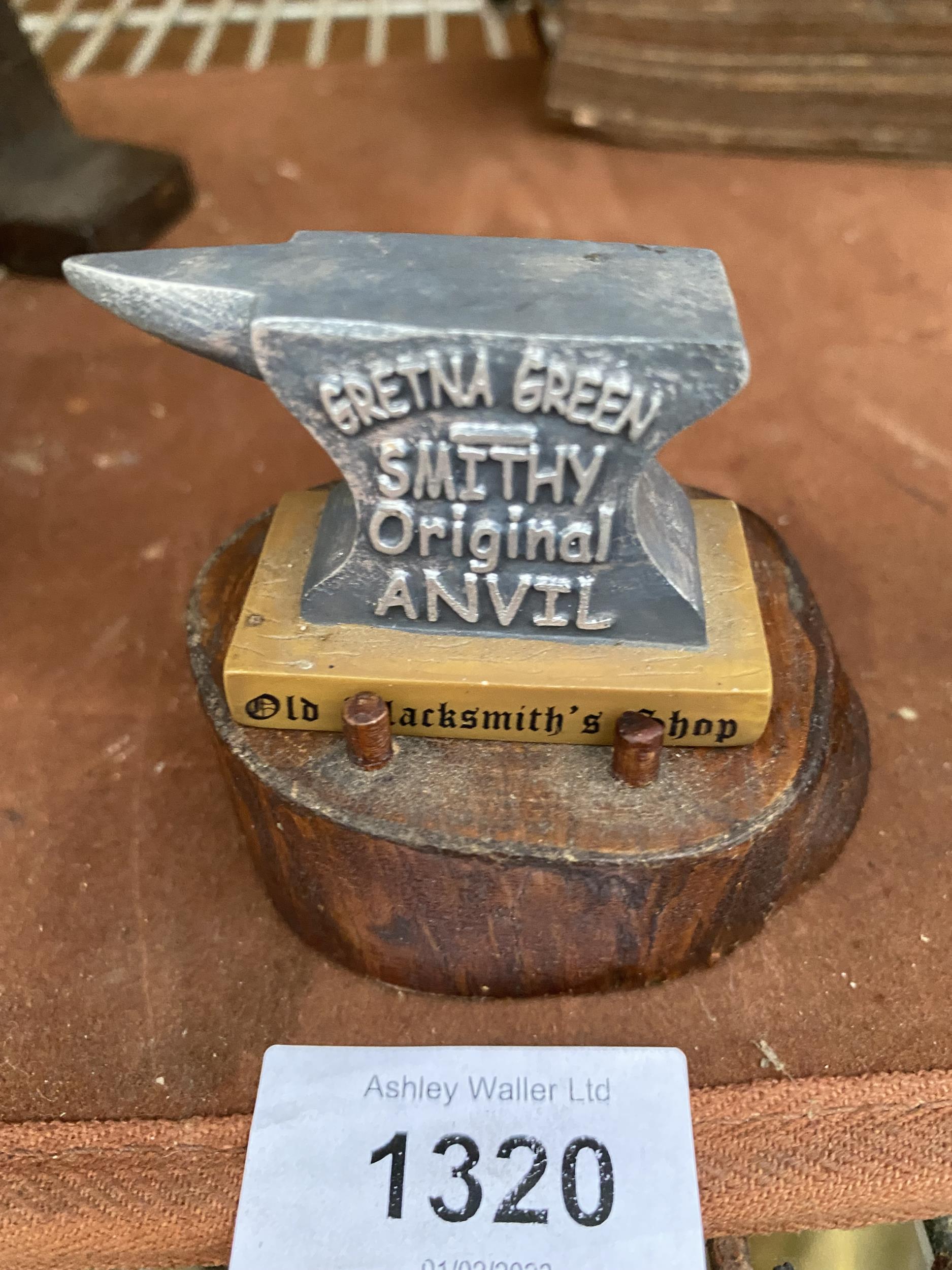 A RESIN SAMPLE GRETNA GREEN ANVIL WITH WOODEN LOG BASE