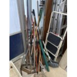 A LARGE ASSORTMENT OF GARDEN TOOLS TO INCLUDE RAKES, BRUSHES AND SPADES ETC