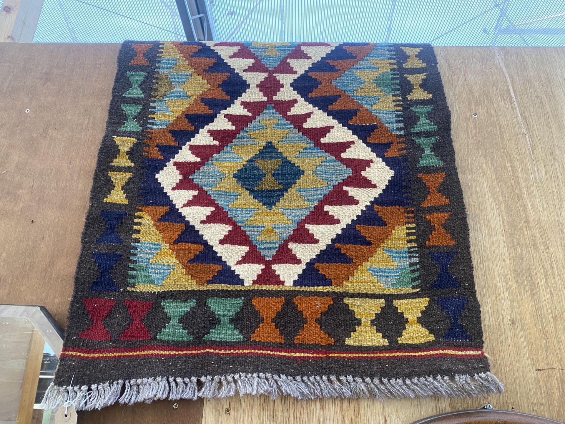 A SMALL PATERNED FRINGED RUG