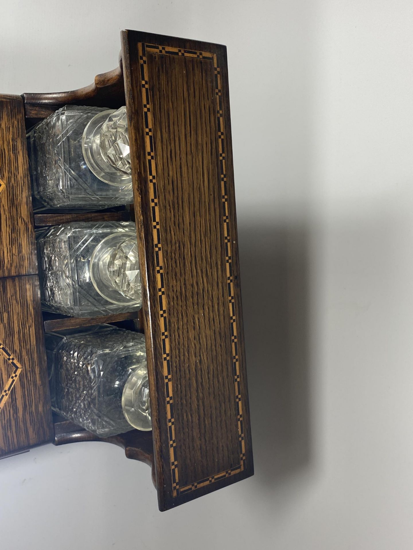 AN EDWARDIAN INLAID OAK THREE BOTTLE TANTALUS HOLDER WITH TWIN LIDDED COMPARTMENT AND LOWER DRAWER - Image 6 of 6