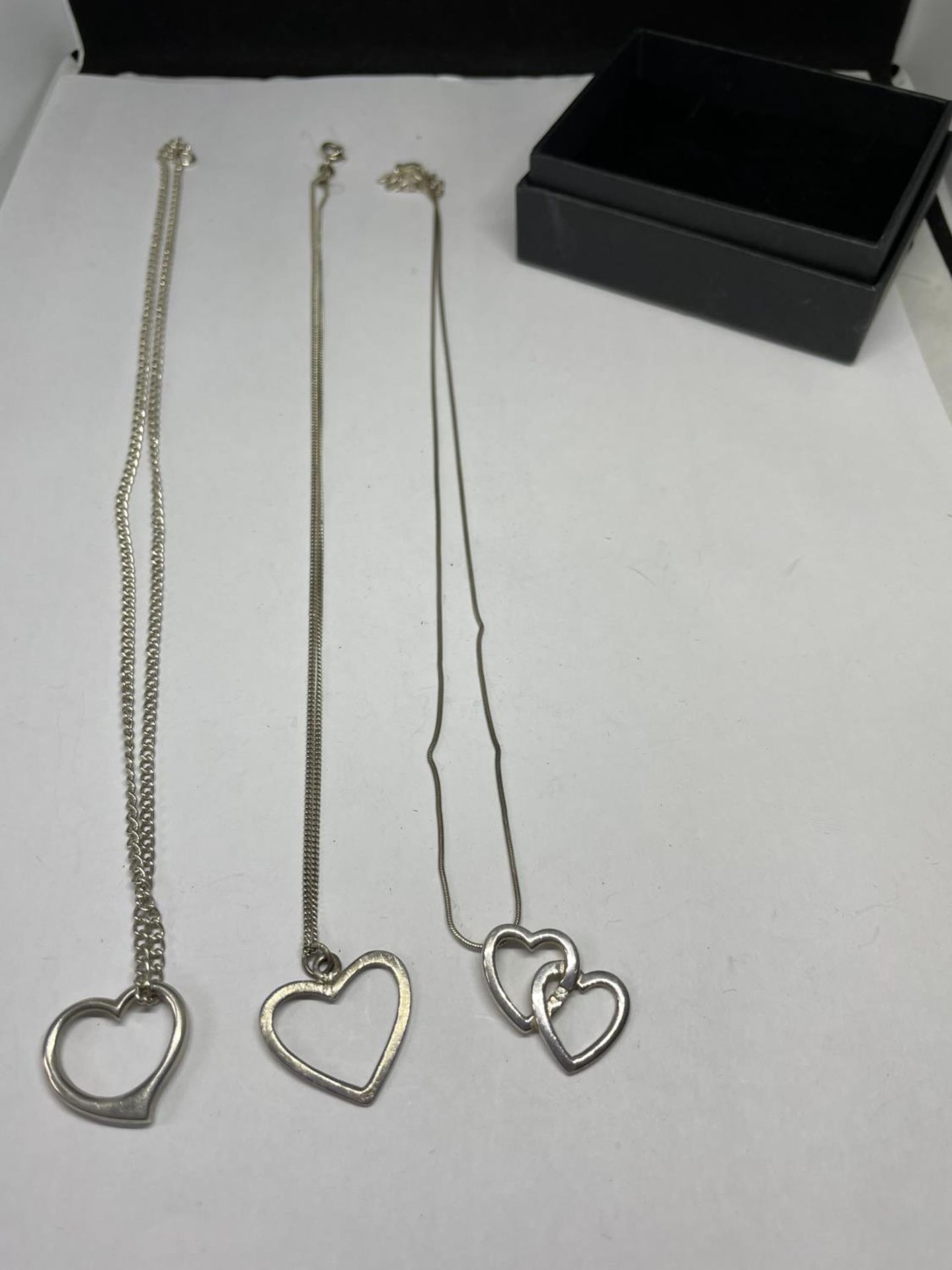 THREE SILVER NECKLACES WITH HEART PENDANTS IN A PRESENTATION BOX